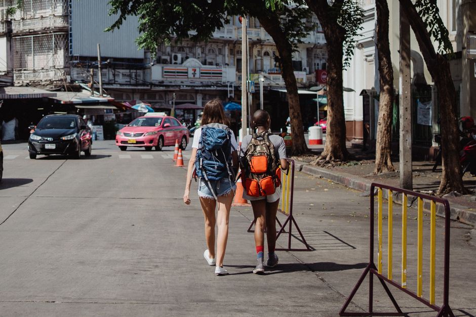Two backpackers walk down a lively street, embodying urban exploration and travel.